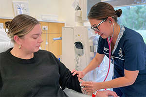 A nurse treats a female patient who is sitting in a treatment chair